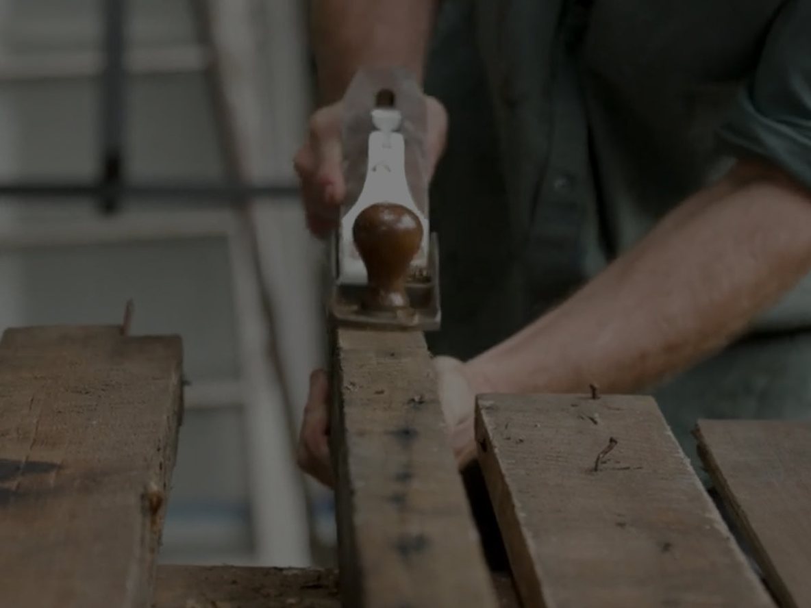 A maker hand-planing timber at the bench